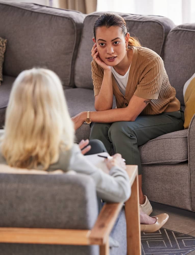 Una sesión de terapia con dos personas sentadas frente a frente y hablando.